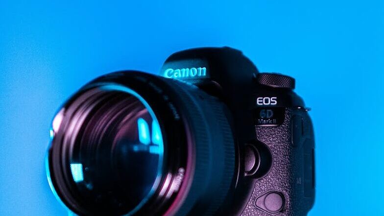 Close-up of a DSLR camera on a tripod with a blue background.